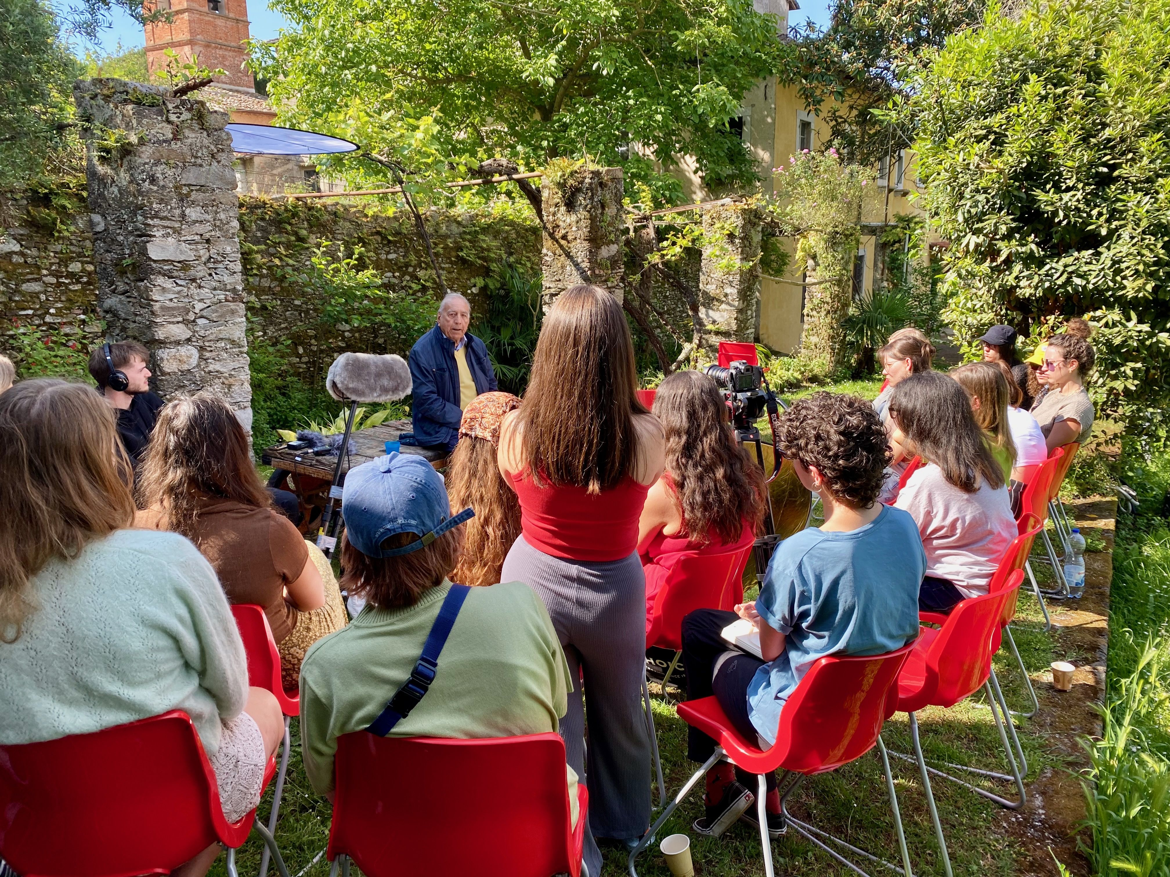 Die Studierenden sitzten in einem italienischen Garten auf roten Stühlen um den Überlebenen Mario Marsili im Halbkreis herum. 